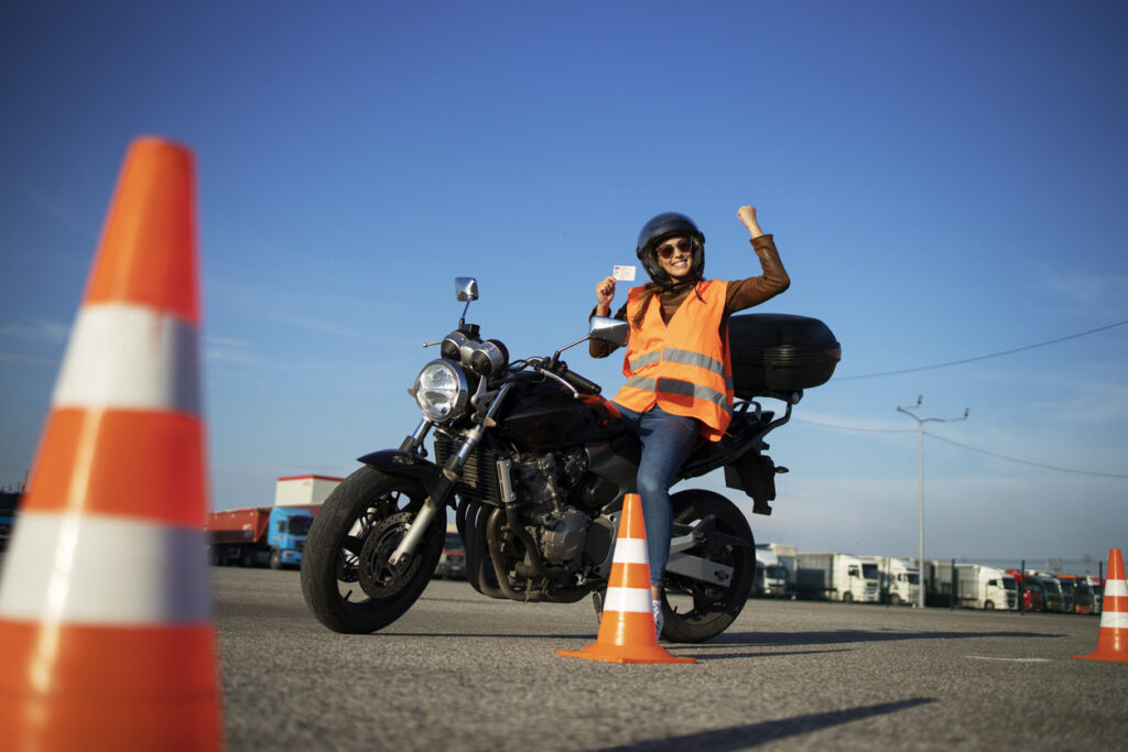 Female student with helmet taking motorcycle lessons and practicing ride