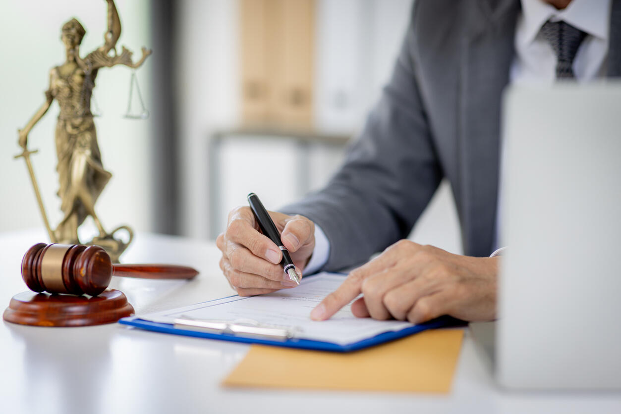 A lawyer signing documents with a gavel and Lady Justice statue, representing the emotional and legal recovery from personal injury.