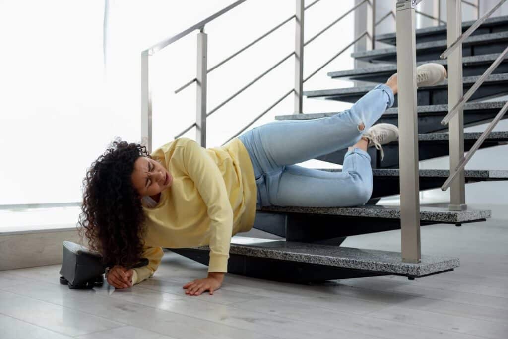 Injured woman on stairs in building after fall. Dangerous accident